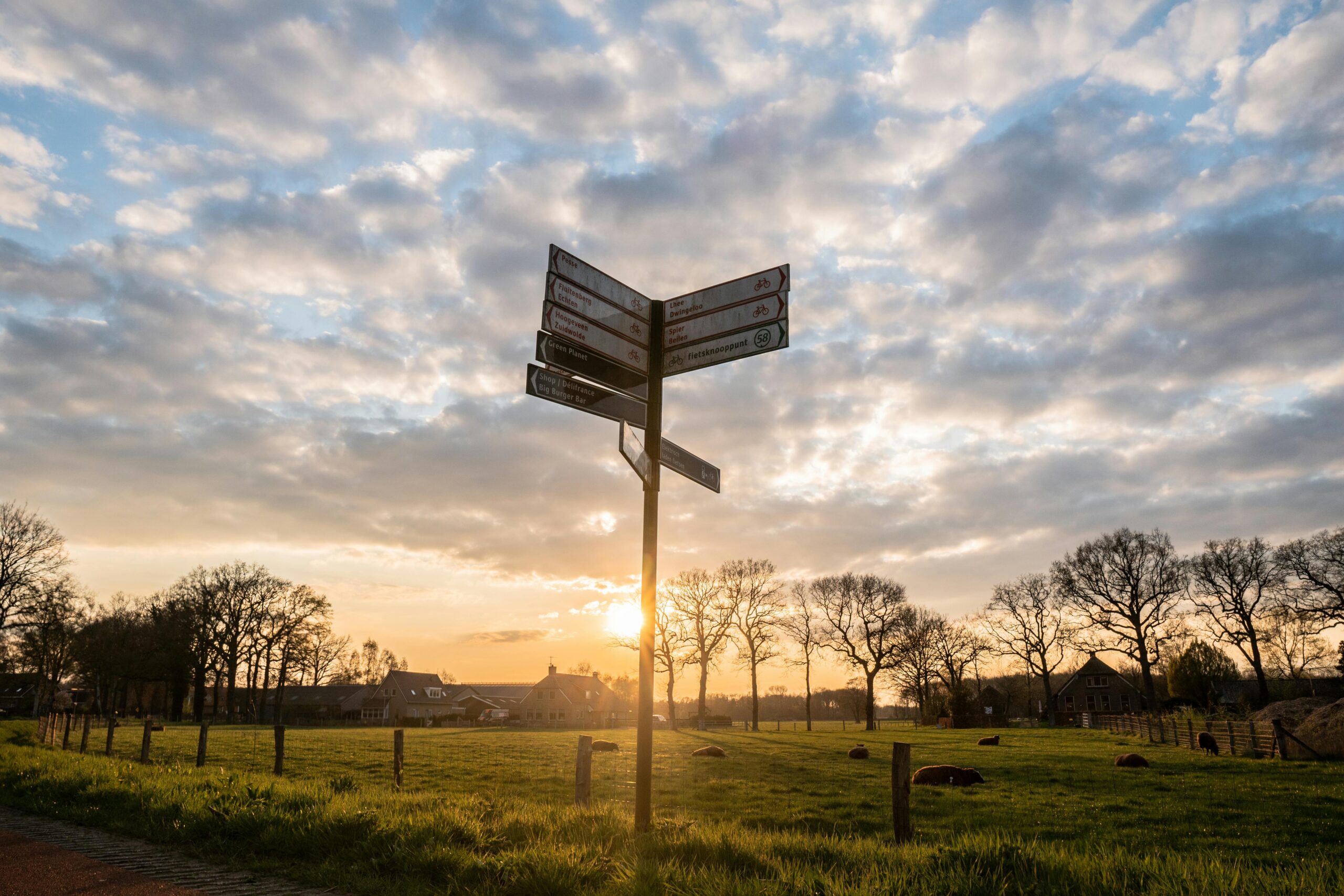 Peaceful rural landscape with a signpost silhouetted against a stunning sunset sky.